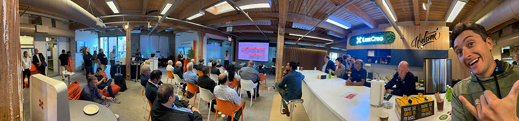 Panoramic view of a conference room with people seated and a person in the foreground.