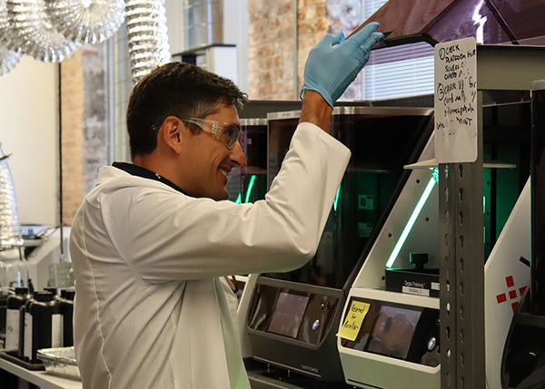 Person in a lab coat interacting with a machine in a laboratory setting