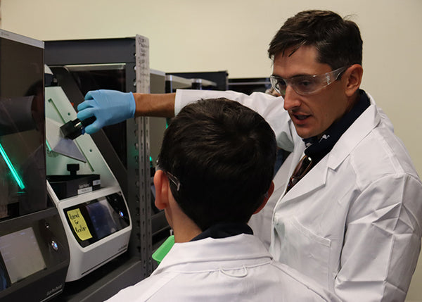 Two scientists in a laboratory setting, examining equipment.